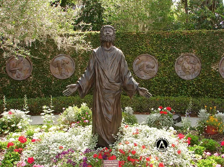 life size statue of a man in a flower bed