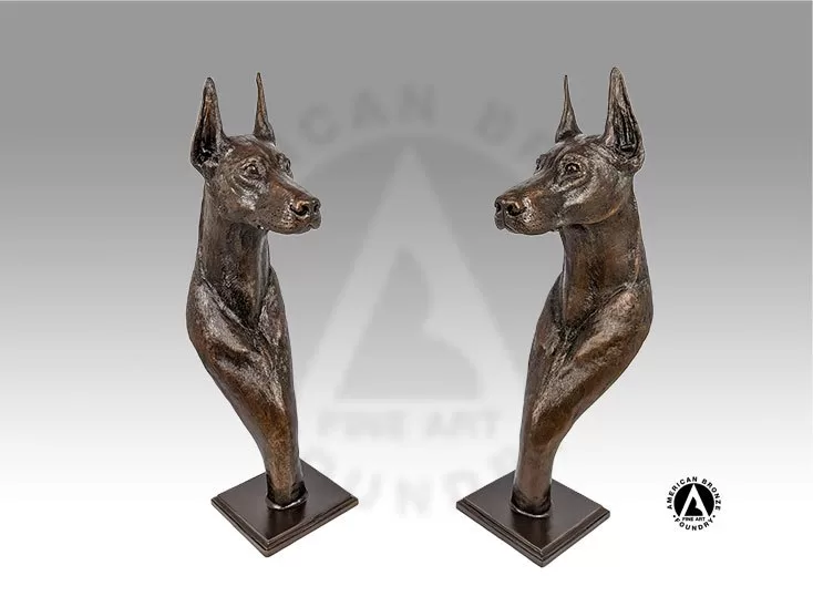 2 brown - bronze doberman busts on a base