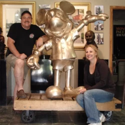 large bronze statue of mickey mouse with owners of the foundry