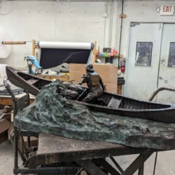Large sculpture of a man rowing a canoe down a river