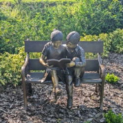bronze kids sitting on a bench reading jungle book repatina and restoration